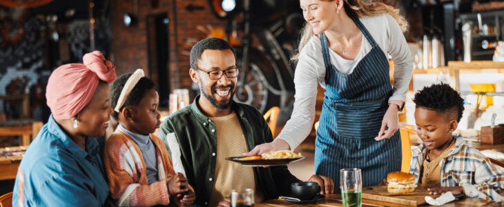 Family, lunch and service of at restaurant with plate, fun and eating at diner together. Customer, table and server at cafe with food for happy African parents, children and relax at gathering