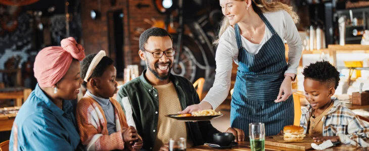 Family, lunch and service of at restaurant with plate, fun and eating at diner together. Customer, table and server at cafe with food for happy African parents, children and relax at gathering