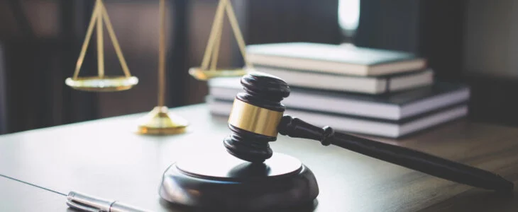 Scales of justice and Gavel on wooden table and Lawyer or Judge working with agreement in Courtroom, Justice and Law concept.